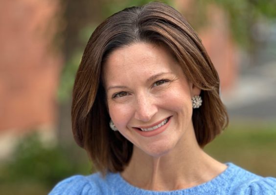 A woman smiles while posing for a headshot outside.