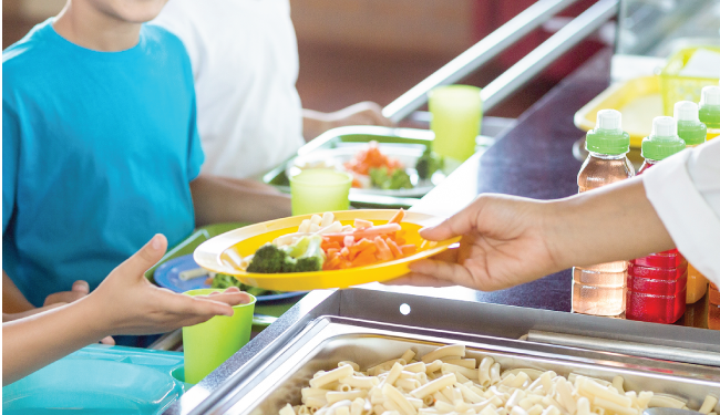 A school lunch worker handing a lunch plate to a child