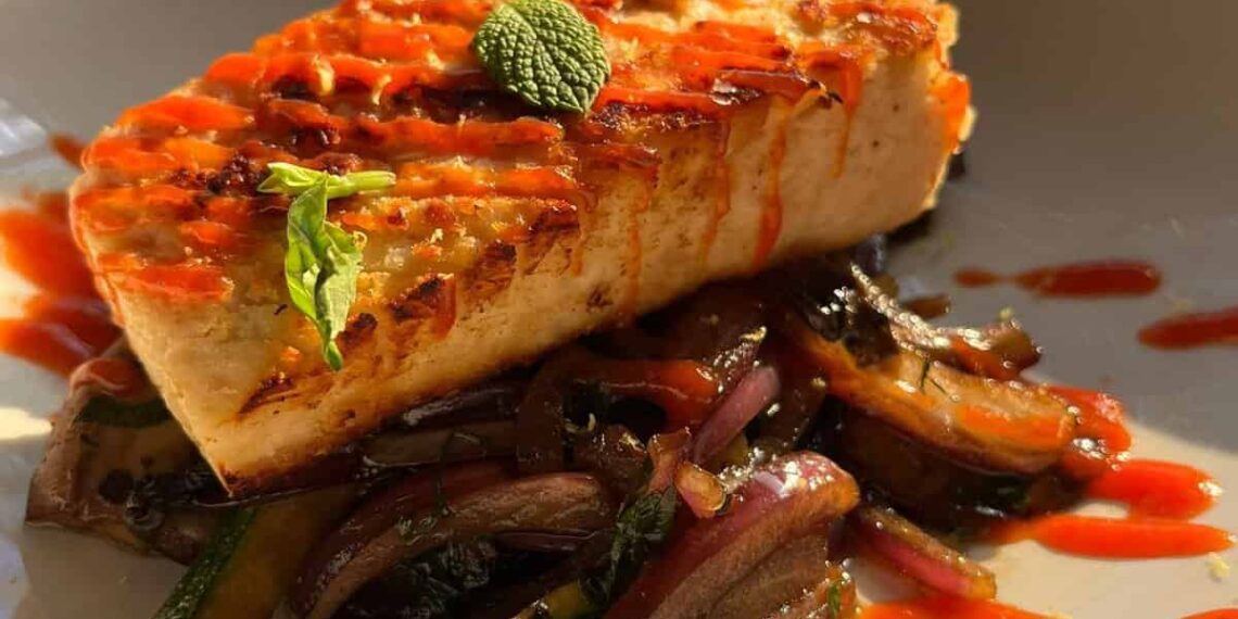 A vegan mycelium white fish filet with sauce.