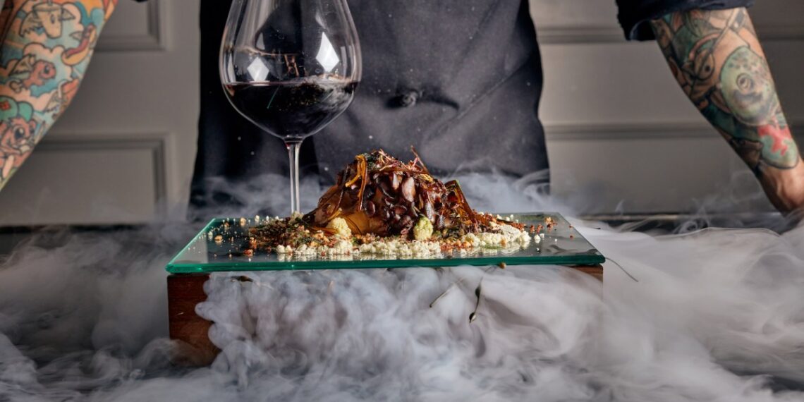 Surf and turf next to a glass of wine surrounded in smoke