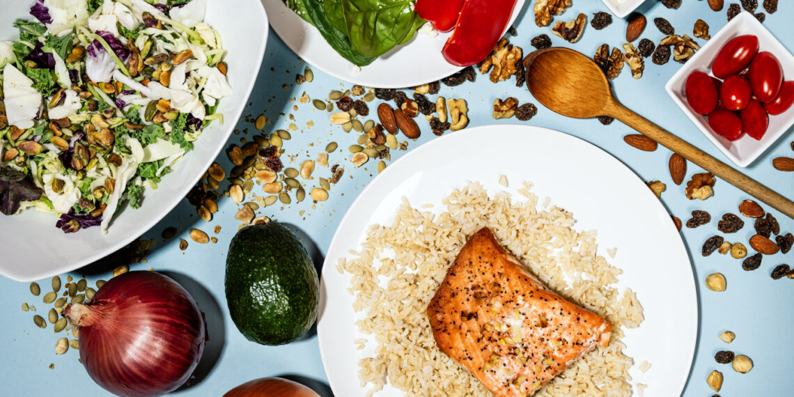 Plates of food from the Mediterranean diet, including salmon on rice and a salad.