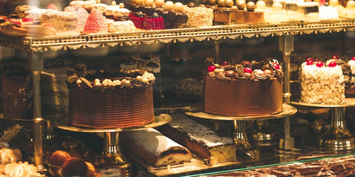 Photo of a pastry shop display window with variety of cakes. Courtesy of Getty Images