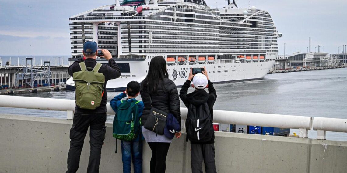 Unos pasajeros hacen fotos al MSC World Europa este viernes en muelle Adossat de Barcelona.