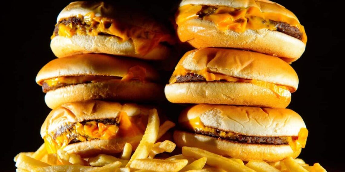A pile of cheeseburgers and french fries.