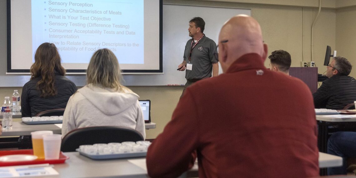 A man lectures from the front of a classroom.