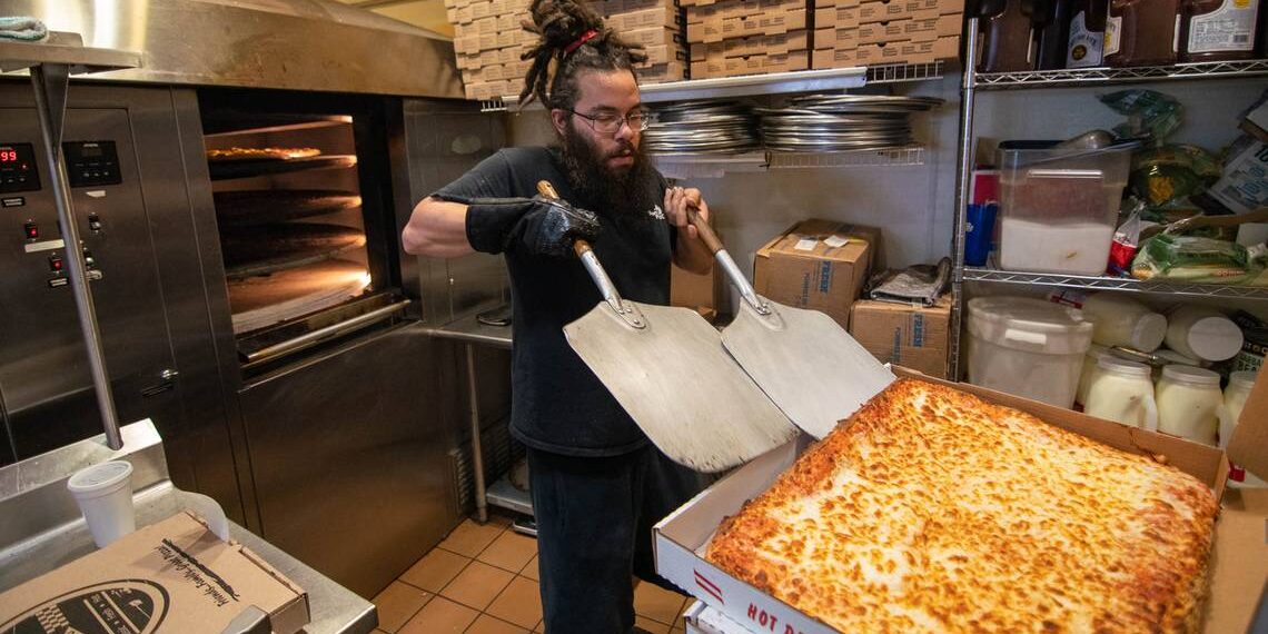 A Bisonte Pizza Co. cheese sheet pizza being cut just out of the oven.