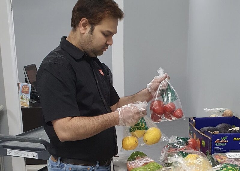 Salvation Army worker puts fruit and vegetable into food box
