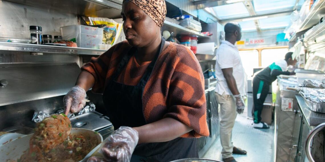 Millicent Twum-Barimah, left, stirs her signature shrimp fried rice as her husband Isaac, middle, and 14-year-old son Eric take orders Thursday in NOTO. Twum-Barimah started KononiaTouch African Cuisine a little over a year ago out of her church kitchen and several months ago opened a food truck.