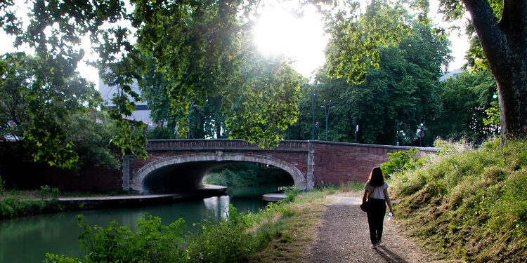 Joven paseando por el Canal de Briennes en Toulouse (Francia), elegida mejor ciudad para viajar en 2025 por Lonely Planet.
