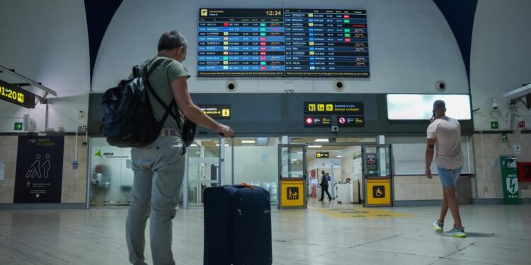 Un turista frente a una de las pantallas de vuelos del aeropuerto de Sevilla.