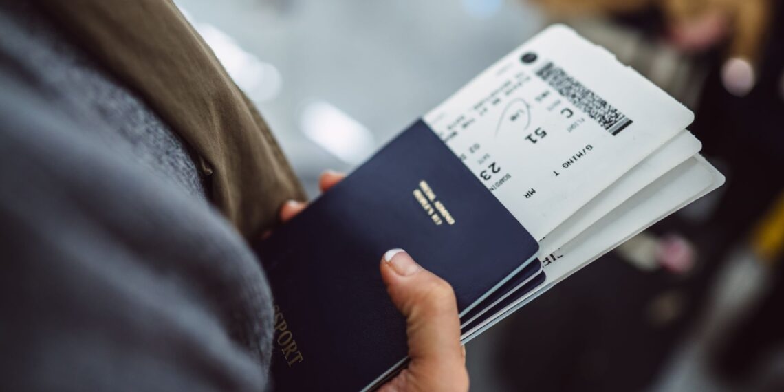 Someone holding a passport with two boarding passes inside it