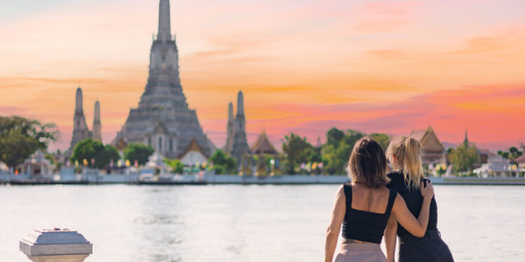 Two women discover Bangkok riding a boat in Chao Phraya river looking out from the boat