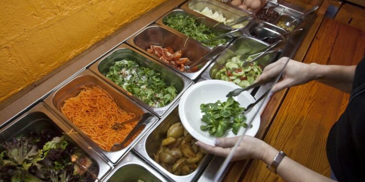Una cliente de un hotel se sirve comida en el buffet de un restaurante.