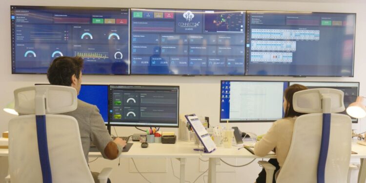 Dos personas trabajando en una oficina con pantallas mostrando datos tur&iacute;sticos