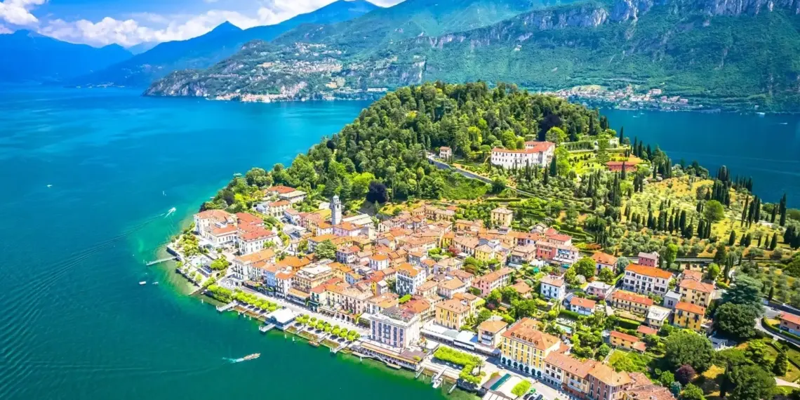 Vista aérea de un pueblo italiano junto al lago, con aguas turquesas, montañas verdes y villas rodeadas de jardines.