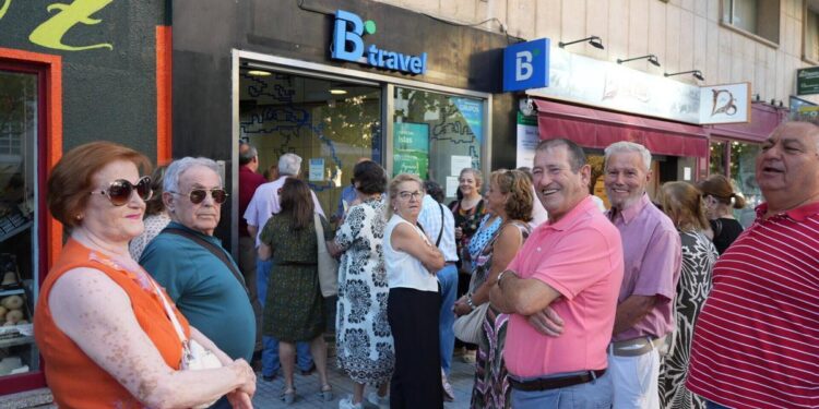 Pacenses esperando a las puertas de una agencia de viajes.