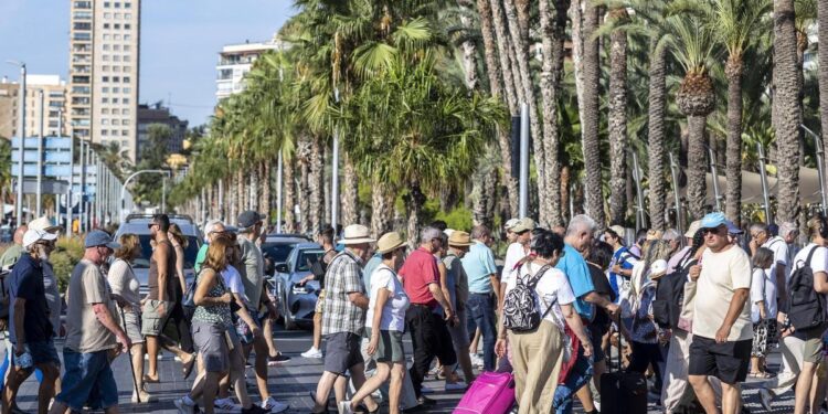 Un grupo numeroso de turistas cruza un paso de peatones en el centro de Alicante