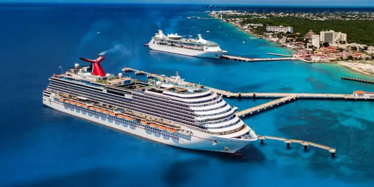 Vista aérea de una terminal marítima con un gran barco de cruceros acoplado al muelle en aguas turquesas frente a la costa.